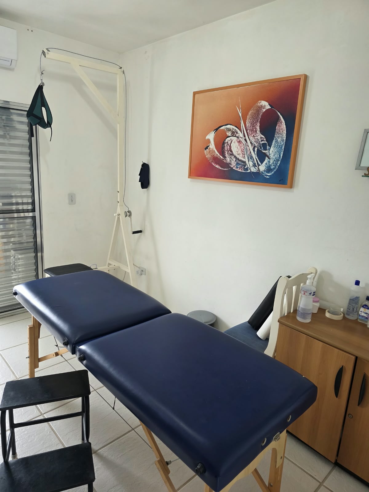 Maca azul e equipamentos suspensos em uma sala do consultório.