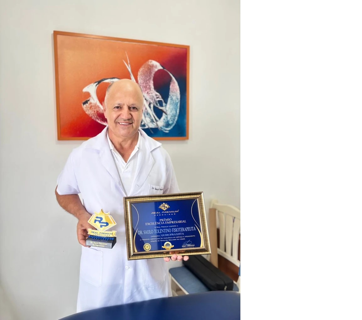 Dr. Saulo, de jaleco branco, segura um troféu e o certificado do Prêmio Excelência Empresarial.